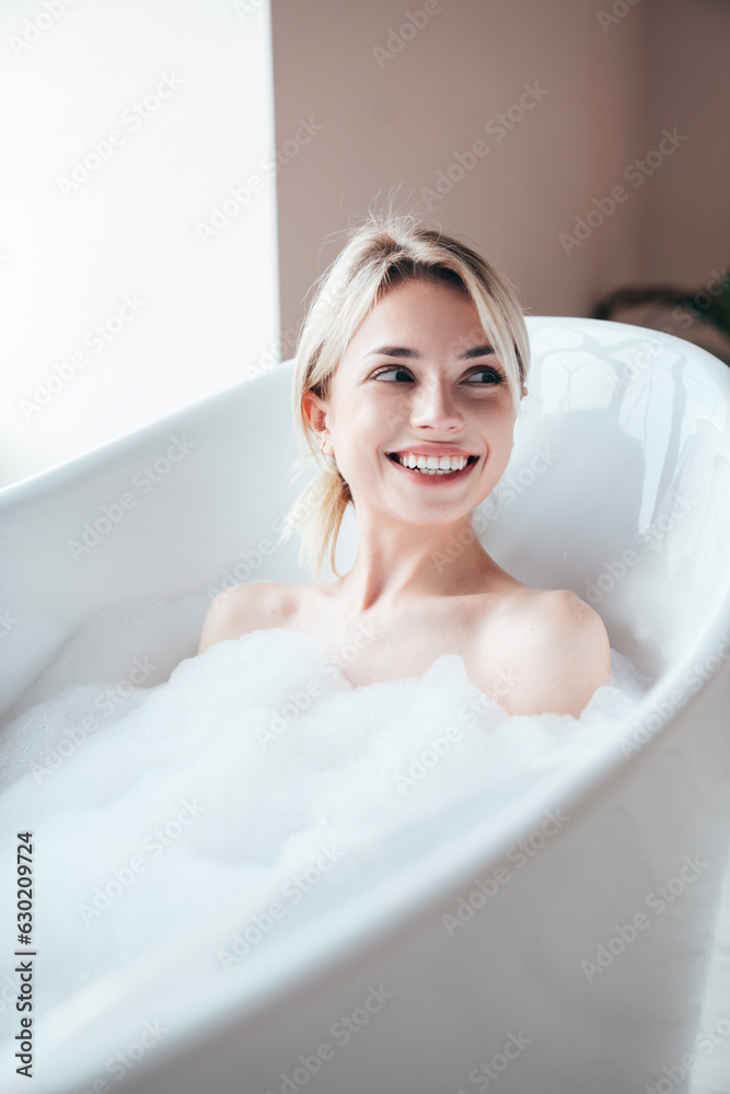 Portrait of young beautiful sexy woman having fun while lying in bathtub full of foam at home. Charming smiling model relaxing in luxury bath interior. Female enjoying beauty and skincare day Portrait of young beautiful sexy woman having fun while lying in bathtub full of foam at home. Charming smiling model relaxing in luxury bath interior. Female enjoying beauty and skincare day