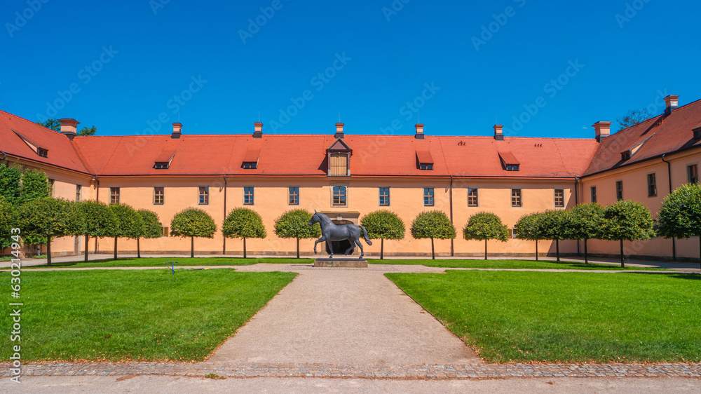 Moritzburg, Saxony, Germany. Old stable with monument of horse near famous ancient Moritzburg Castle, main entrance, near Dresden at sunny summer day with blue sky