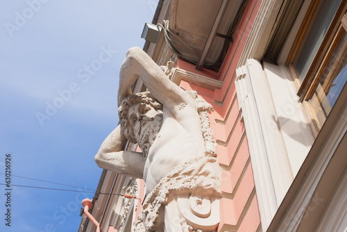Atlant, Atlas or Titan sculpture on pink historic building. Male man sculpture with beard. view from below from street