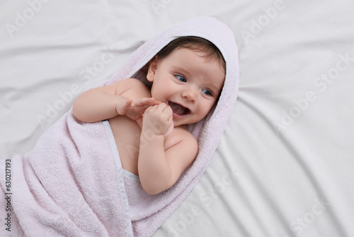 Cute little baby with pacifier in hooded towel after bathing on bed, top view