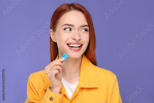 Beautiful woman with bubble gum on purple background