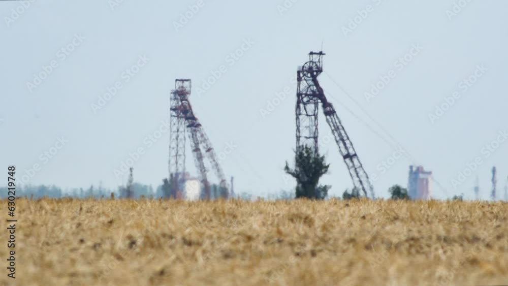 Mirage or heat waves over field with harvested crop of grain crops on extreme hot summer weather. Steel headframes of iron ore mines on horizon. Global warming and climate change concept video. Mirage or heat waves over field with harvested crop of grain crops on extreme hot summer weather. Steel headframes of iron ore mines on horizon. Global warming and climate change concept video.