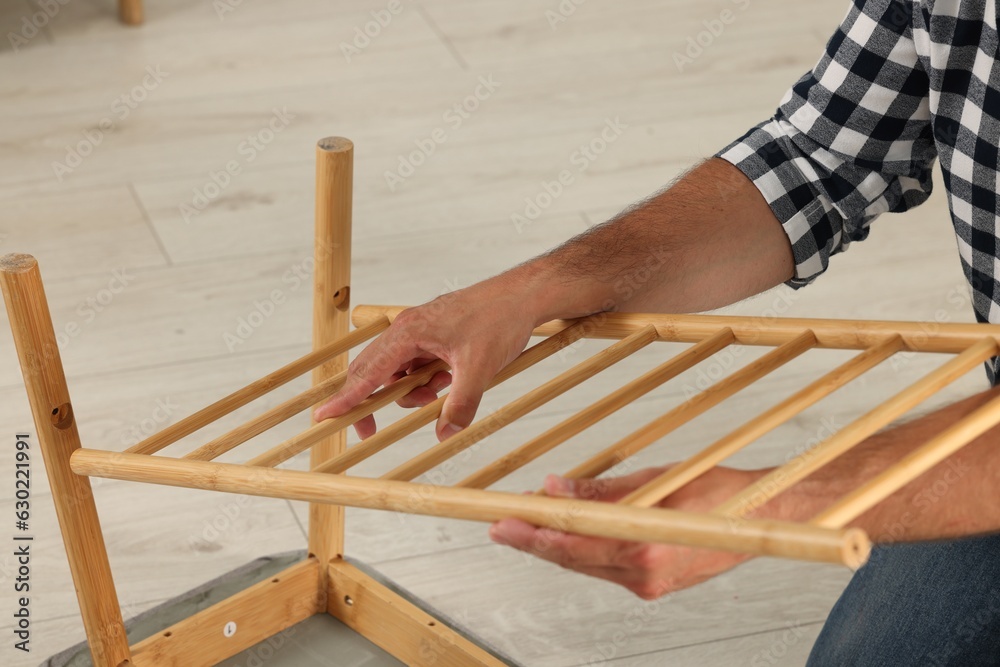 Man assembling shoe storage bench on floor, closeup Man assembling shoe storage bench on floor, closeup