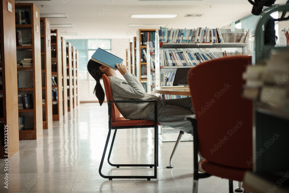 © Thanumporn - Asian student woman read books in library at university. Young girl stress tired have problem while study hard. Sadness concept