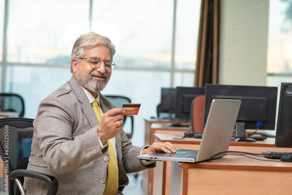 Senior Businessman using laptop and bank card at office Senior Businessman using laptop and bank card at office