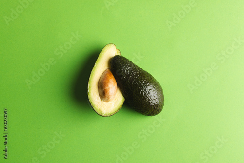 Close up of two halves of avocado and copy space on green background