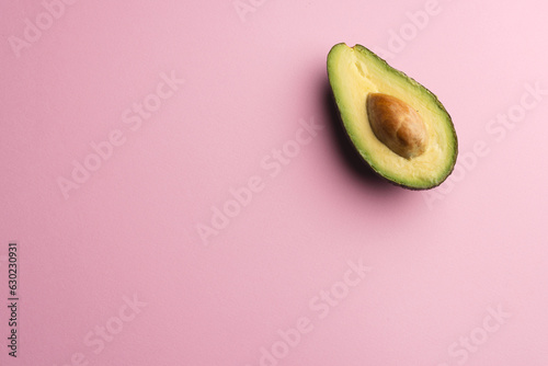Close up of half of avocado and copy space on pink background