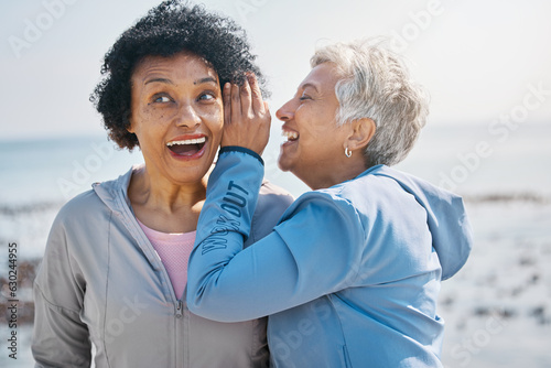 Gossip, beach and senior friends with a secret, whisper or talking in ear for a funny joke after outdoor exercise. Laughing, crazy and elderly women listening to conversation or story at the sea photo
