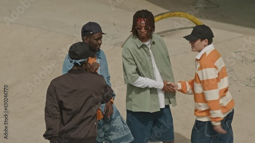 High angle shot of multiracial dudes shaking hands and embracing each other for goodbye outdoors in street