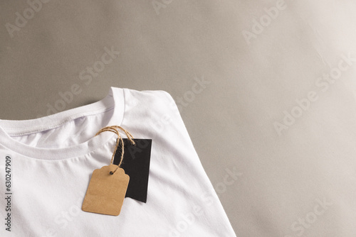 Folded white t shirt with tags with copy space on brown background