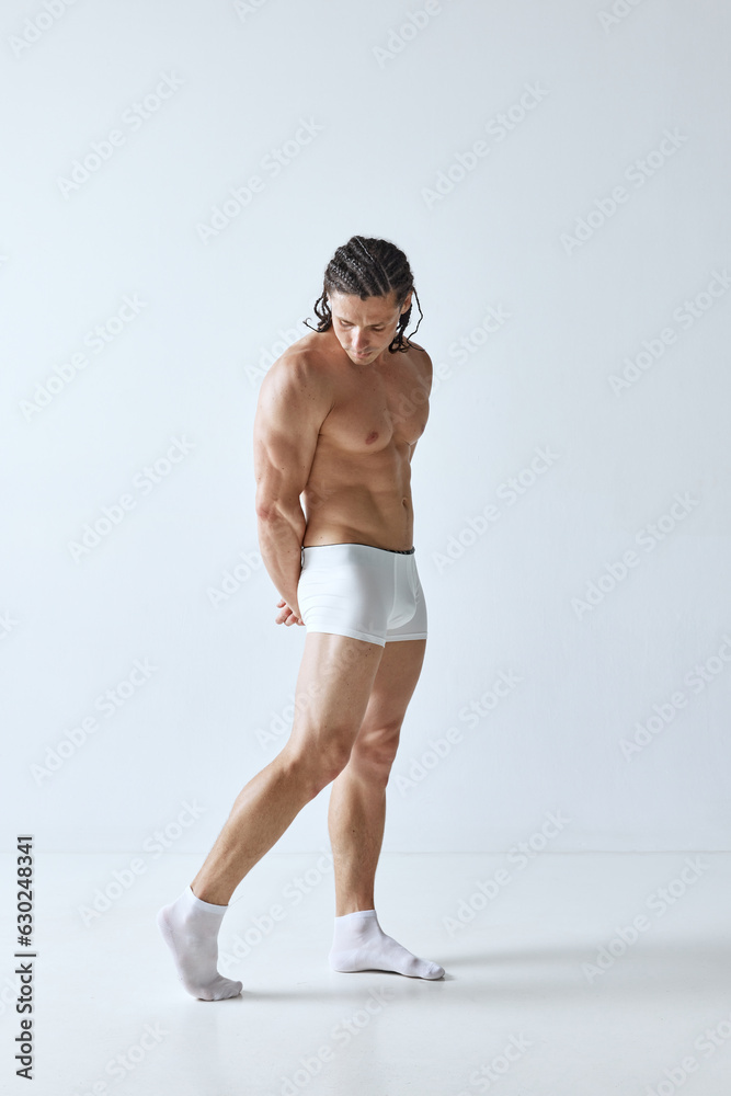 Full-length portrait of handsome mature man with muscular strong body standing shirtless in boxers against grey background. Concept of men's beauty, body care, sport, wellness, healthy lifestyle, ad Full-length portrait of handsome mature man with muscular strong body standing shirtless in boxers against grey background. Concept of men's beauty, body care, sport, wellness, healthy lifestyle, ad