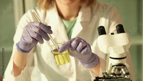 Laboratory researcher holds medical glass bottle with yellow liquid. Scientist examining urinalysis photo
