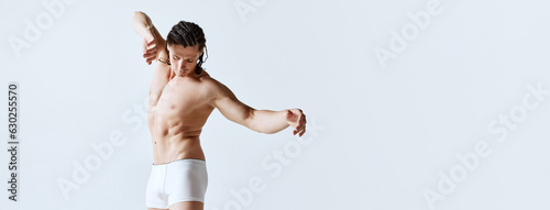 Mature man posing shirtless in underwear against grey studio background. Male model with muscular body shape. Concept of men's beauty, body care, sport, wellness, healthy lifestyle, ad. Banner photo