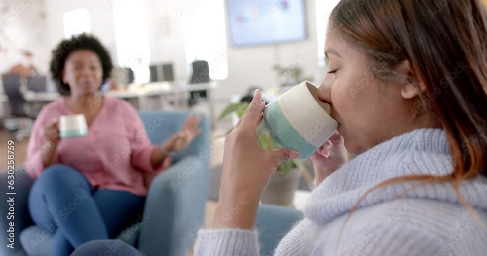 Diverse business female colleagues drinking coffee and talking in office, slow motion Diverse business female colleagues drinking coffee and talking in office, slow motion