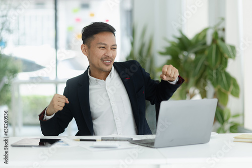 Success and excited Asian man sitting in creative office, Excited businessman or winner celebrate winning. 