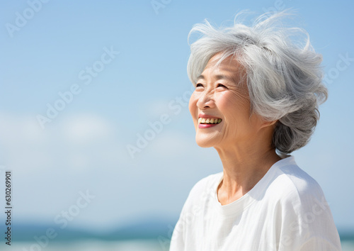 風が吹く空の下で笑顔の日本人シニア女性