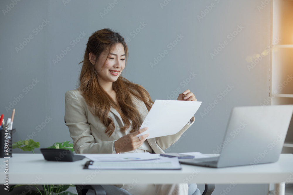 Portrait of candid happy asian woman smiling and holding a paperwork sitting in office. Portrait of candid happy asian woman smiling and holding a paperwork sitting in office.