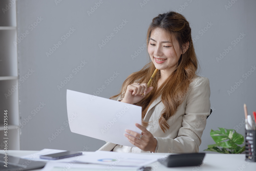 Portrait of candid happy asian woman smiling and holding a paperwork sitting in office. Portrait of candid happy asian woman smiling and holding a paperwork sitting in office.