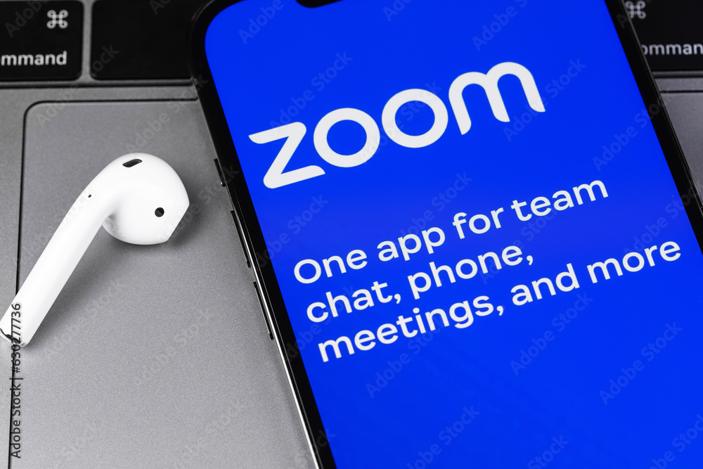Zoom mobile icon app on a screen smartphone iPhone with AirPods closeup