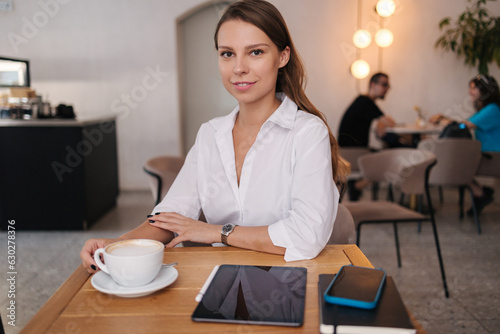 Young business lady working in cafe. Attractive woman in white shirt. Formal portrait 