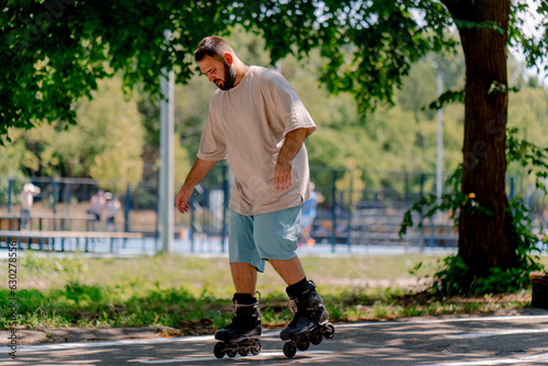 Young guy with a beard learns to rollerblade in a city park concept of wanting to learn new things and body positivity 