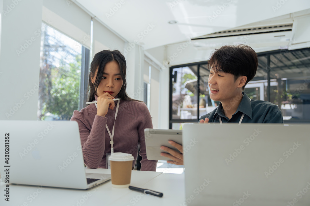 Employees discuss brainstorming planning business strategy on laptop at desk together in the office Employees discuss brainstorming planning business strategy on laptop at desk together in the office