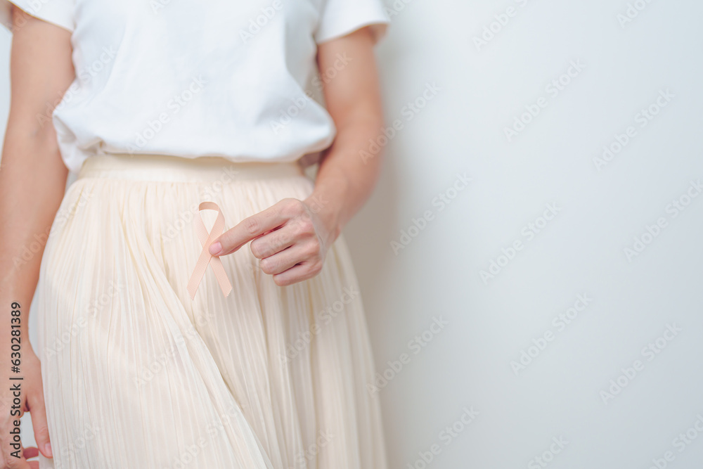 Woman holding Peach Ribbon on abdomen for September Uterine Cancer Awareness month. Uterus and Ovaries, Cervix, Endometriosis, Hysterectomy, Uterine fibroids, Reproductive and World cancer day concept Woman holding Peach Ribbon on abdomen for September Uterine Cancer Awareness month. Uterus and Ovaries, Cervix, Endometriosis, Hysterectomy, Uterine fibroids, Reproductive and World cancer day concept
