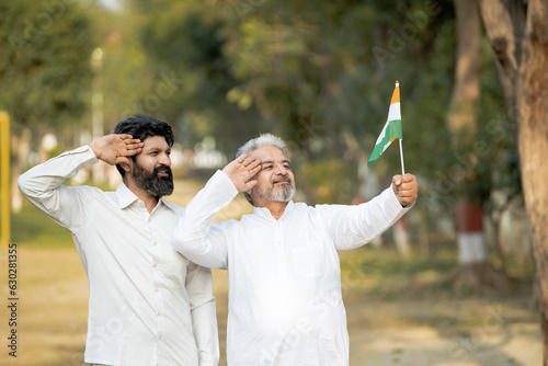 Two indian men saluting of national tricolor flag.
