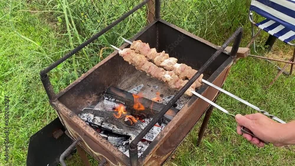 Grilling barbecue and placing a new skewer on the grill Grilling barbecue and placing a new skewer on the grill
