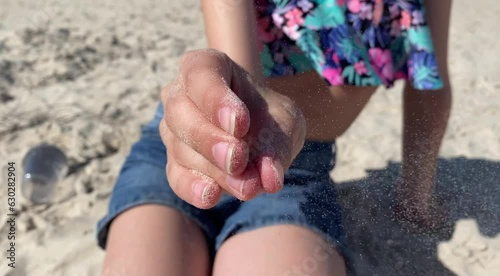 She rubs a small heart out of the sand with her hands