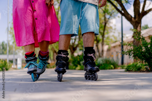 Close-up Young couple boyfriend and girlfriend rollerblading in summer in a city park while dating a plus size models