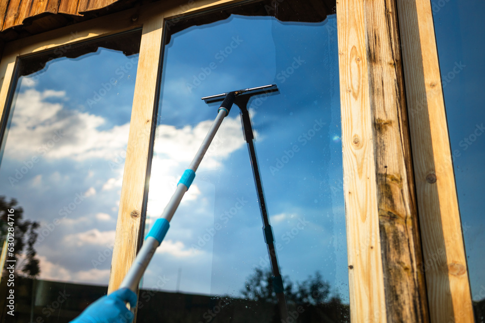 Cropped view of woman hand equipment for washing and cleaning the window from the outside Cropped view of woman hand equipment for washing and cleaning the window from the outside