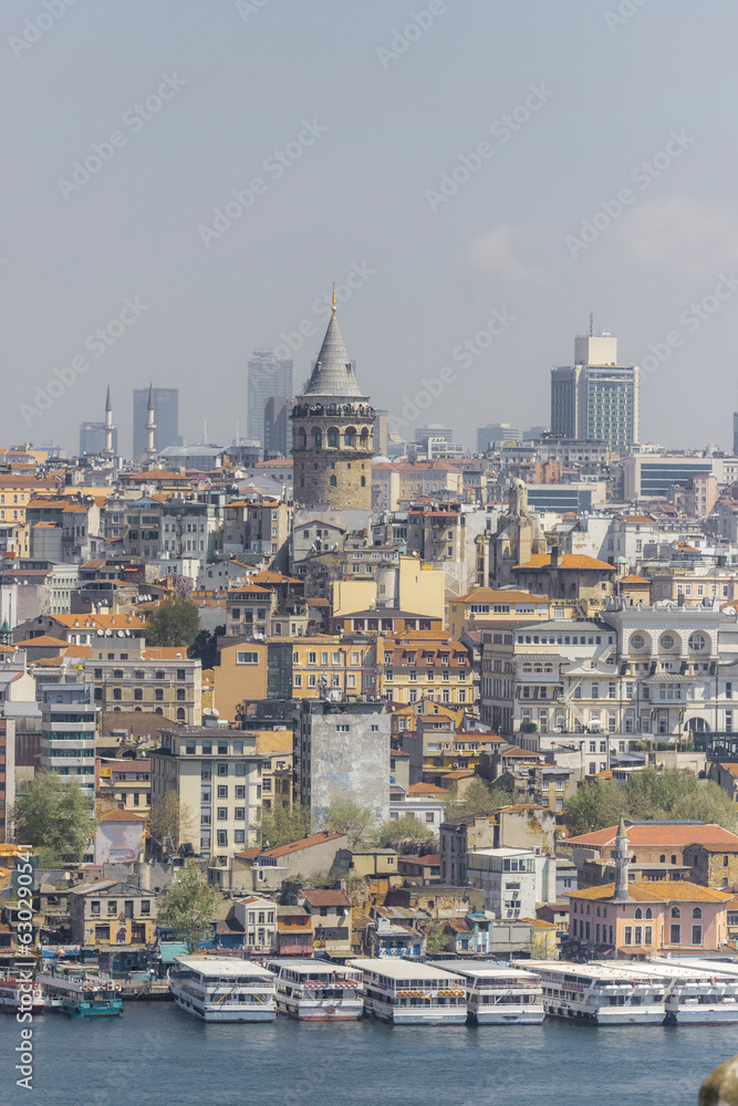View of the Galata Tower in Beyoglu district along the Golden Horn Strait with boats along the pier in Istanbul downtown, Turkey. View of the Galata Tower in Beyoglu district along the Golden Horn Strait with boats along the pier in Istanbul downtown, Turkey.