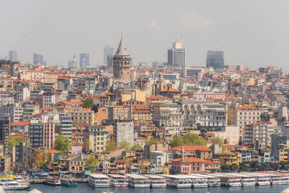 View of the Galata Tower in Beyoglu district along the Golden Horn Strait with boats along the pier in Istanbul downtown, Turkey. View of the Galata Tower in Beyoglu district along the Golden Horn Strait with boats along the pier in Istanbul downtown, Turkey.