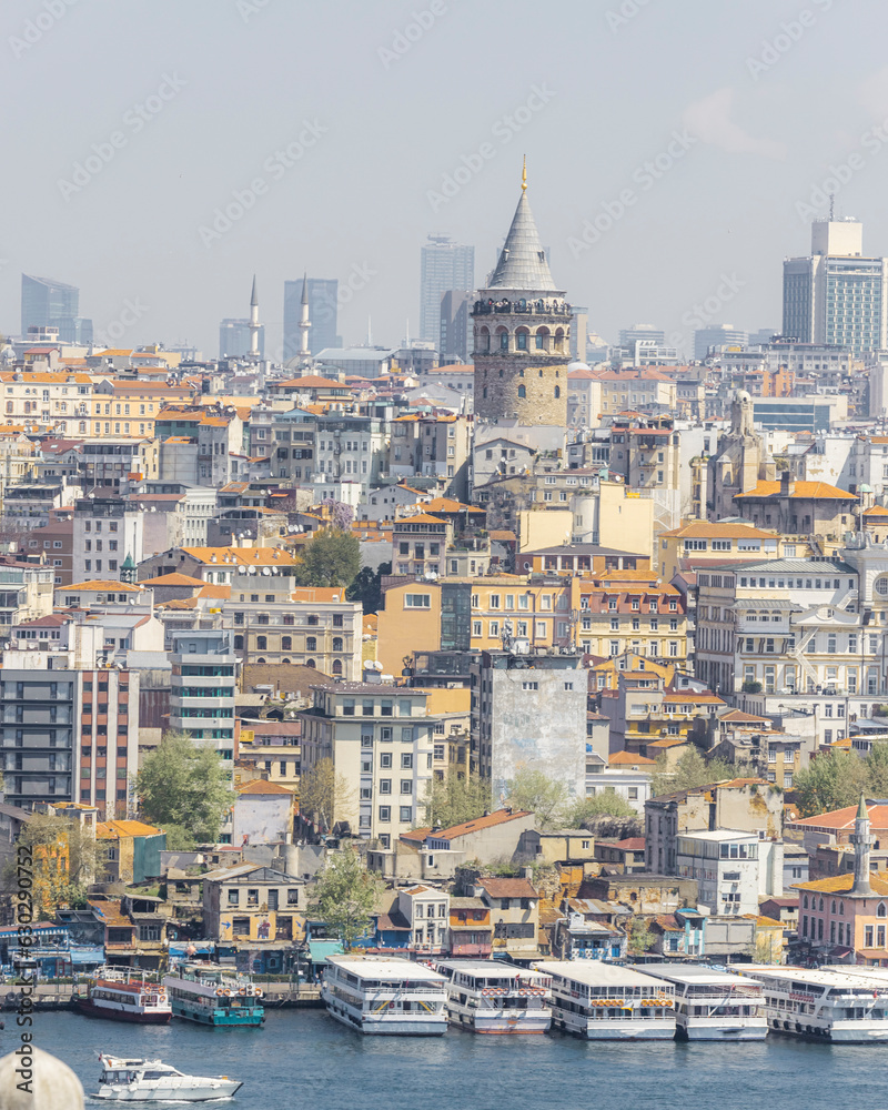 View of the Galata Tower in Beyoglu district along the Golden Horn Strait with boats along the pier in Istanbul downtown, Turkey. View of the Galata Tower in Beyoglu district along the Golden Horn Strait with boats along the pier in Istanbul downtown, Turkey.