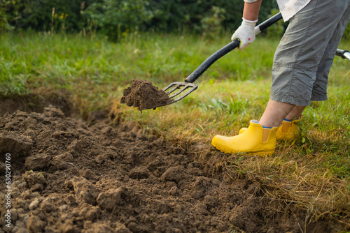 Farmer cultivating land in the garden with hand tools. Soil loosening. Gardening concept. Rake and spade on loosened soil closeup. Agricultural work on the plantation.