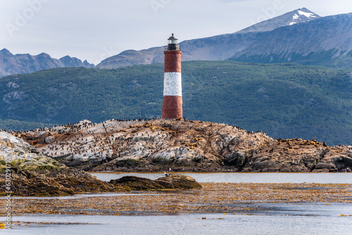 View of Les Eclaireurs Lighthouse with Cormorants and Sea Lions on the rocks, a famous landmark on Beagle channel near Ushuaia, Tierra del Fuego, Patagonia, Argentina. photo
