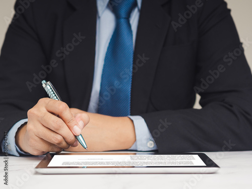 Businessman signature electronic contract on a digital tablet while sitting at the table.