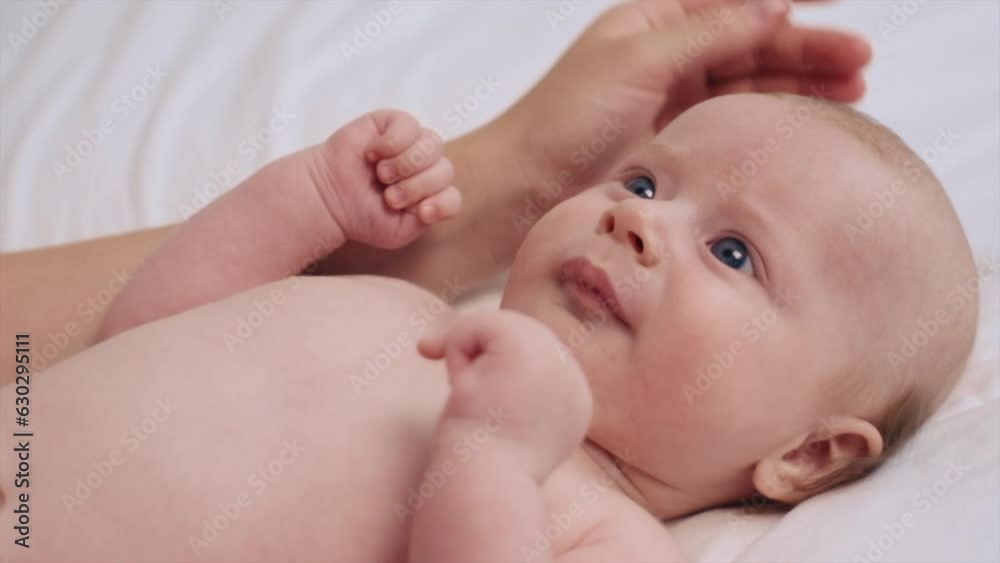 Unknown loving mother and positive adorable few month baby resting together on bed with white sheet at home. New dad enjoying leisure time with little infant kid in bedroom, lying on back, laughing Unknown loving mother and positive adorable few month baby resting together on bed with white sheet at home. New dad enjoying leisure time with little infant kid in bedroom, lying on back, laughing