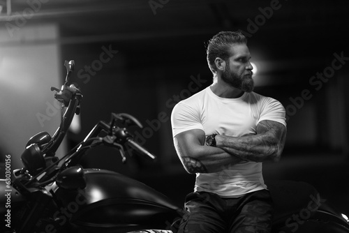 Athletic bearded biker man riding motorbike isolated on indoor parking