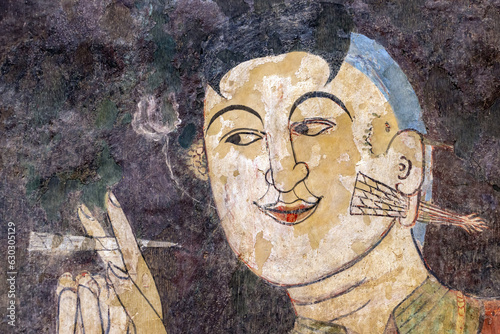 A man smokes a cigarette, mural painting from 19th century inside a Buddhist temple The Wat Phumin, Nan, Thailand photo