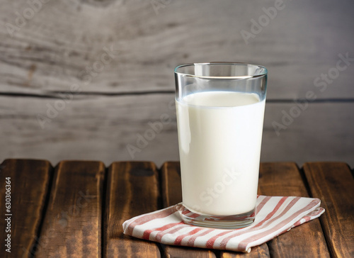 big glass of milk with napkin on old wooden table. Dairy product