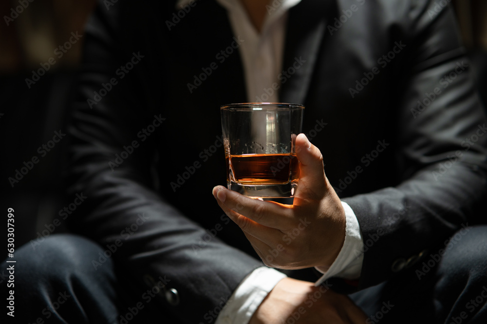 Businessman sitting and holding glass of whiskey.. Businessman sitting and holding glass of whiskey..