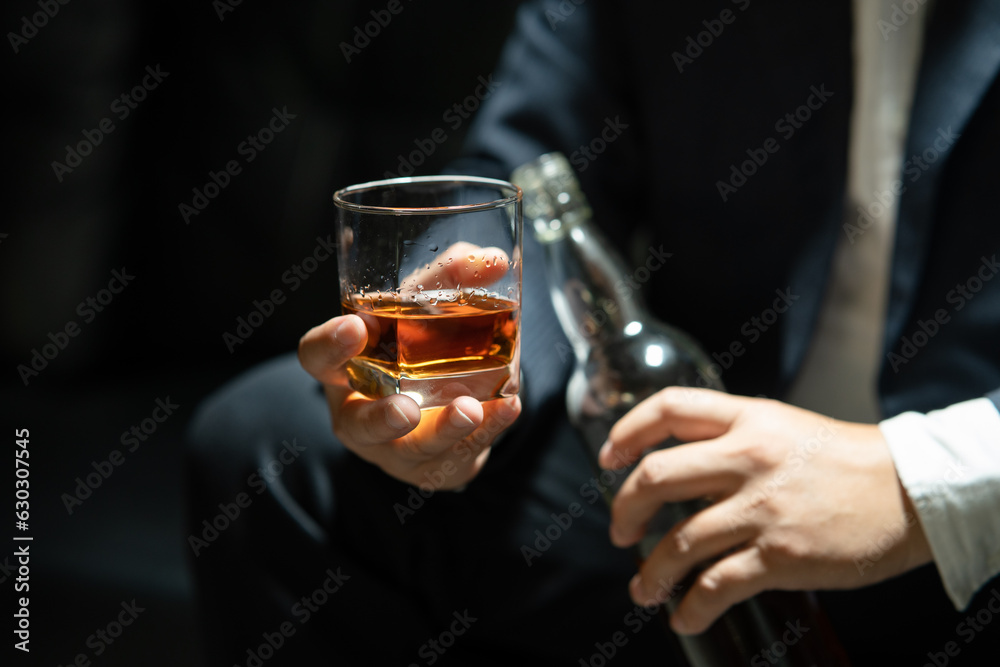 Businessman sitting and holding glass of whiskey..