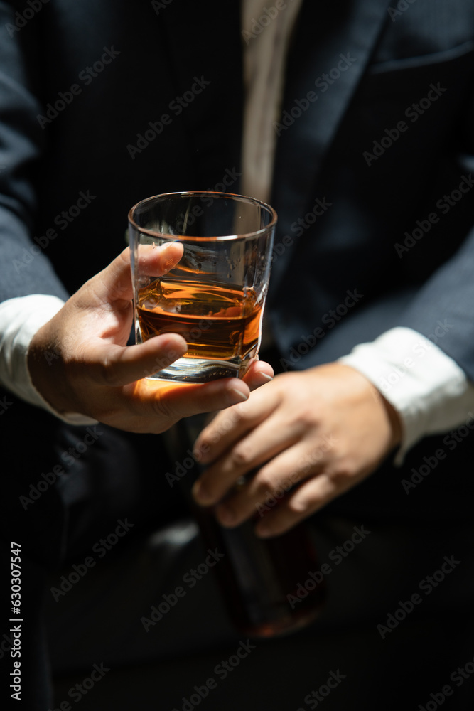 Businessman sitting and holding glass of whiskey..