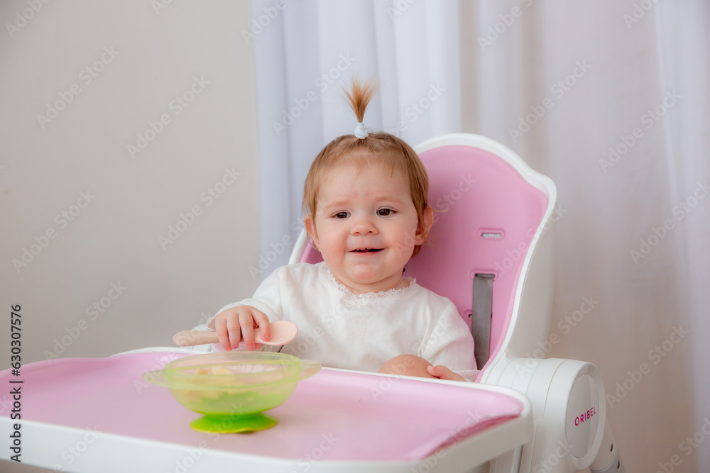 cute baby eats in a high chair made of silicone baby dishes. Baby food, space for text cute baby eats in a high chair made of silicone baby dishes. Baby food, space for text