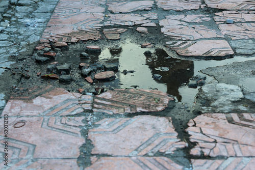 Damaged or broken sidewalk tiles, causing stagnant water.