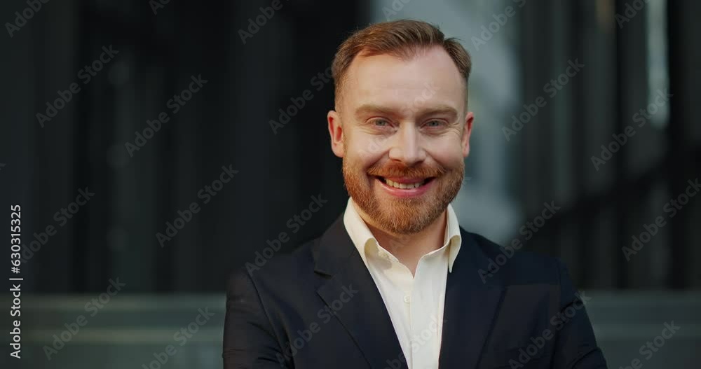Portrait of smiling businessman with red beard and mustache standing outside. Portrait of smiling businessman with red beard and mustache standing outside.