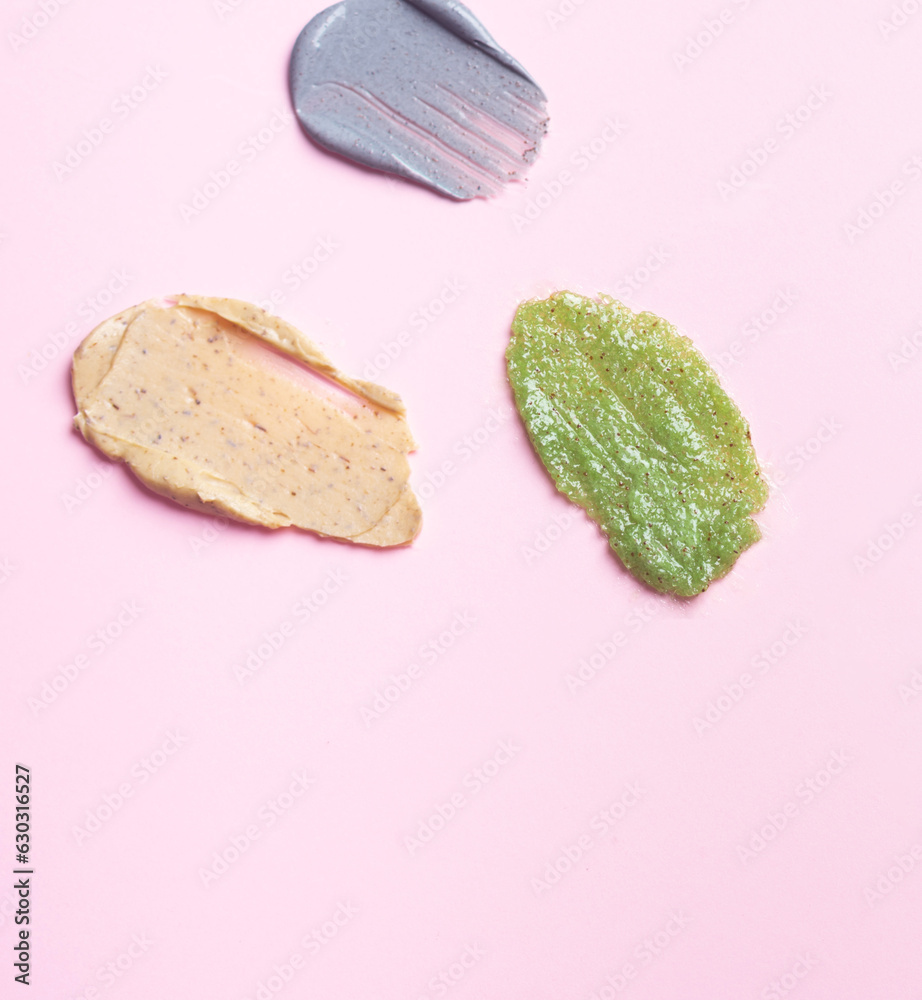 Set multicolored smears of scrub on a pink background. Texture of skin care cosmetic product. Set multicolored smears of scrub on a pink background. Texture of skin care cosmetic product.