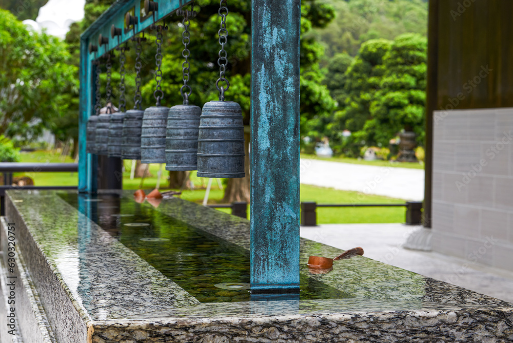 Fototapeta premium Close up of the water tribute pond at Tsz Shan Monastery in Hong Kong with wooden water spoon and chimes